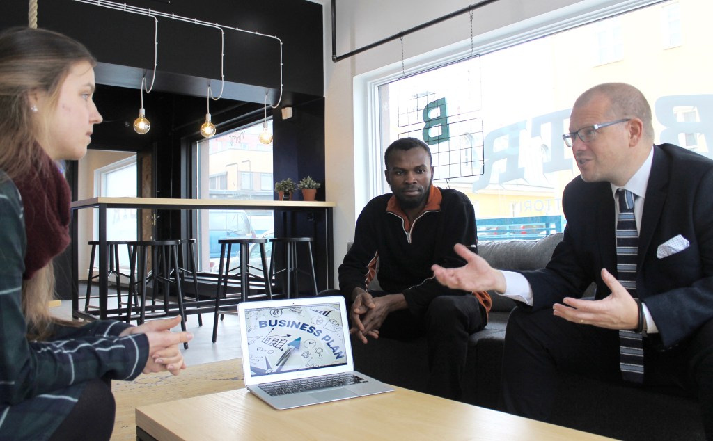 Mark Wiltshear sitting around a low table coaching a young man and a young woman.